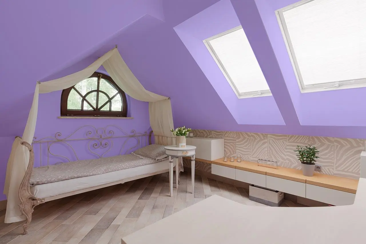 Attic bedroom with lavender walls, skylights and a canopy daybed