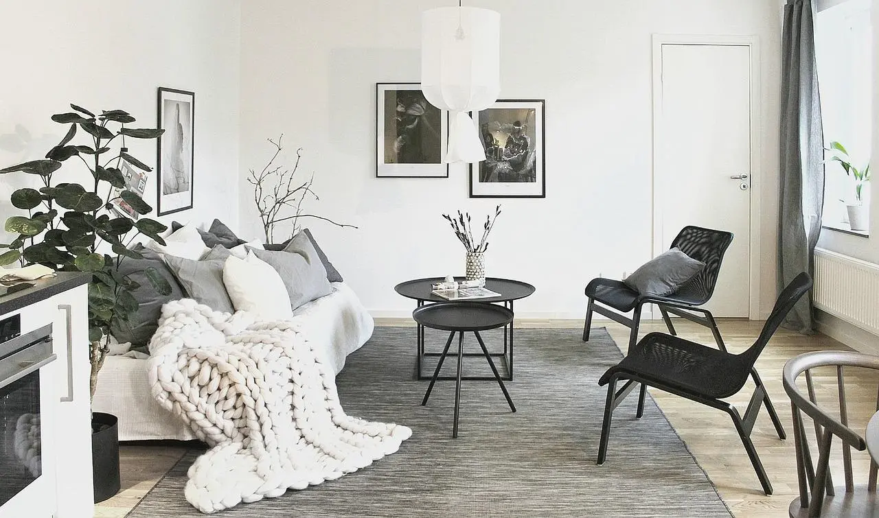 Scandinavian living room with a white sofa, knitted throw and black chairs