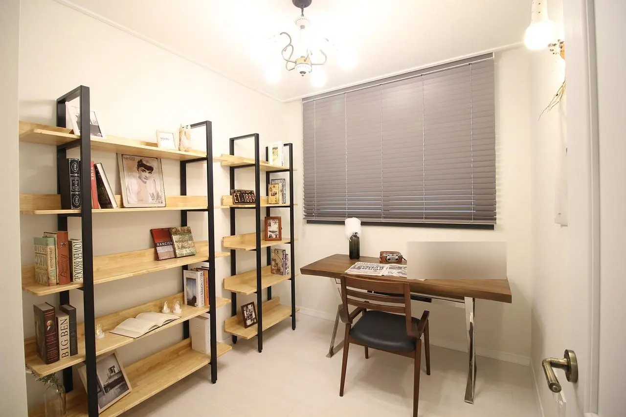 Small study with metal and wood bookshelves, a wooden desk and window blinds