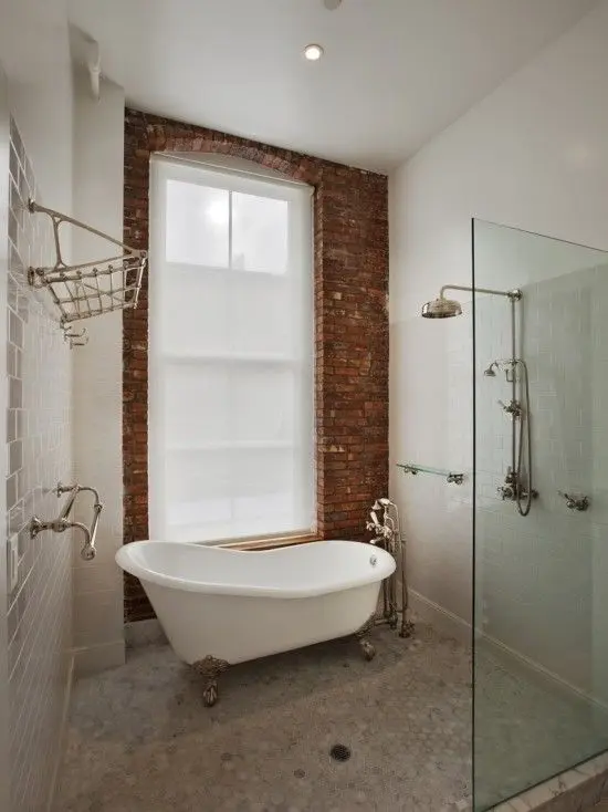 Bathroom with bath and shower: a clawfoot bathtub beside a separate glass walk-in shower and a brick wall