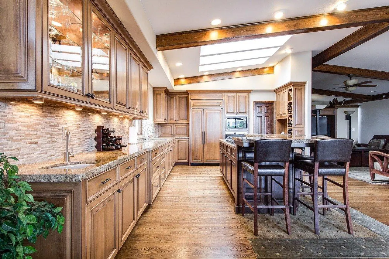 Large wooden kitchen with granite worktops, a hardwood floor and leather bar stools at the island