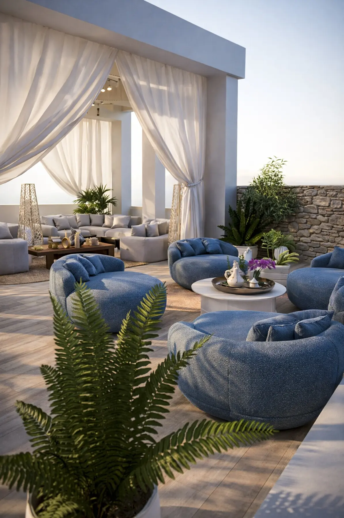 Espaço de estar em deck de madeira com poltronas azuis redondas, cortinas leves e Parede de pedra