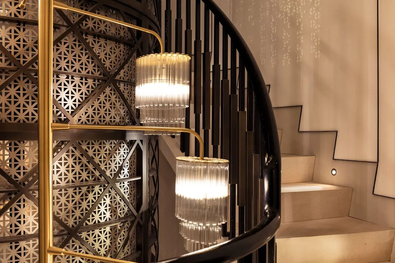 Spiral staircase with geometric lattice panels and glass pendant lights: geometric patterns in interior design with a classic element