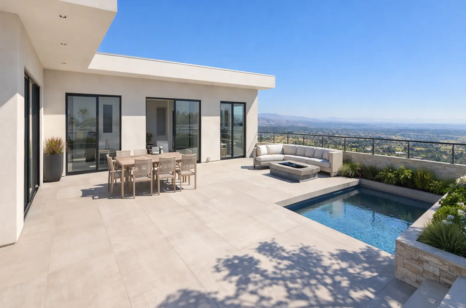 Terraço no topo da colina com mesa de jantar, sofá ao redor de uma lareira e uma pequena piscina