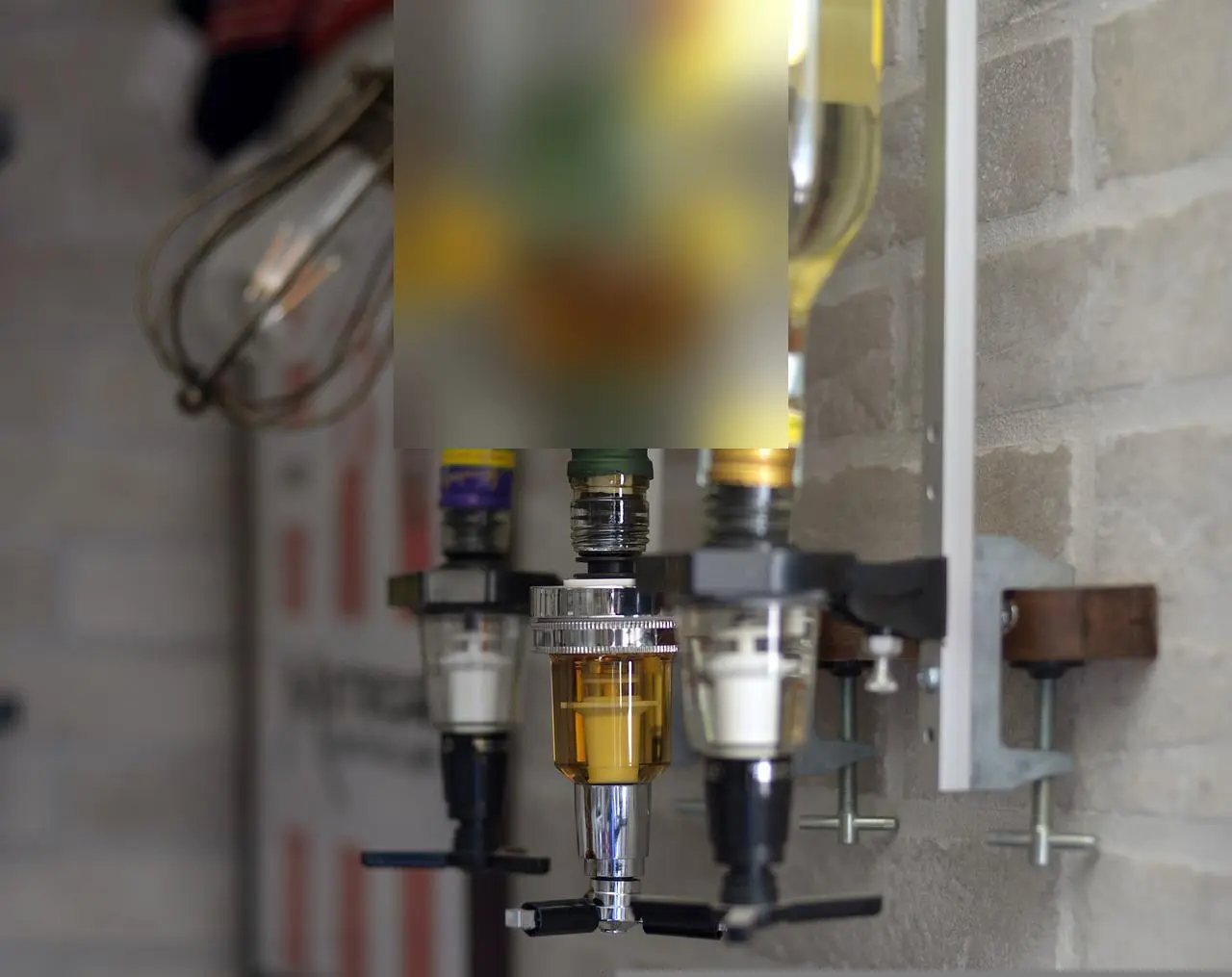 Wall-mounted bar dispenser holding upside-down bottles of spirits